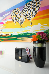 bright balloon abstract painting with purse and flower pot in foreground