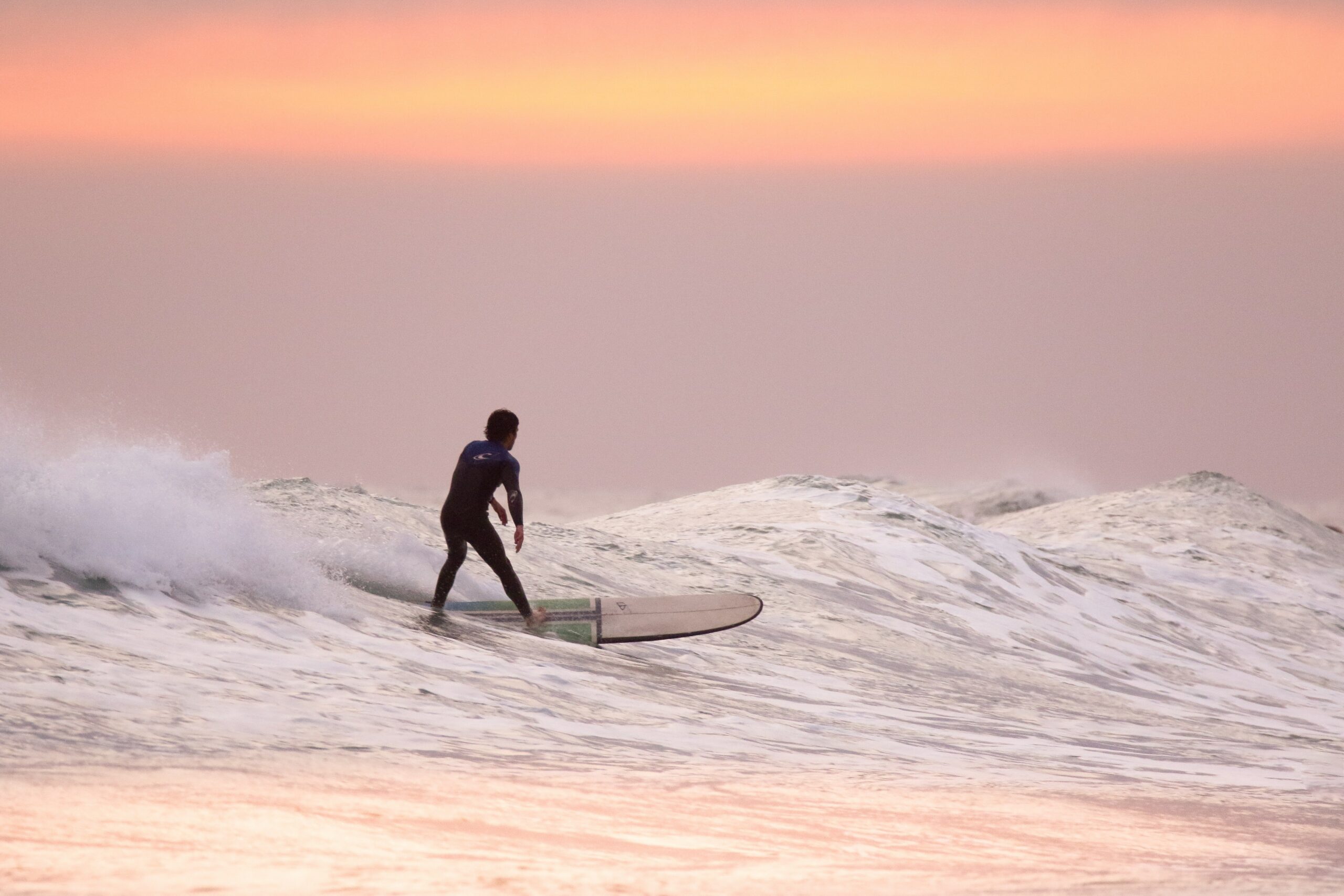 hawaii surfer crossing waves at sunset