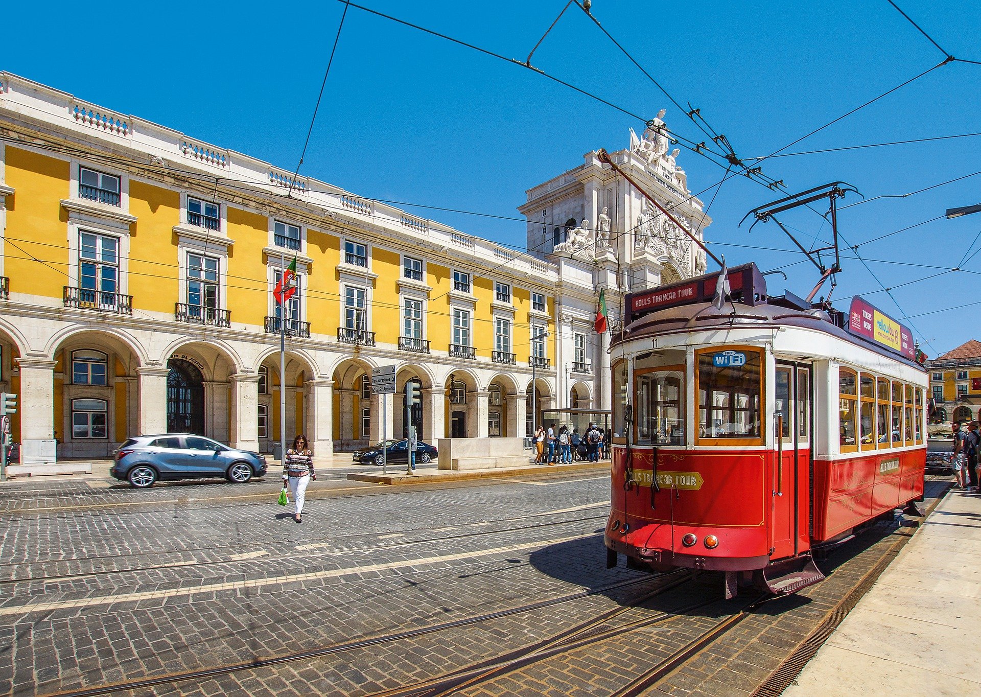 red tram passing a yellow building in portugal