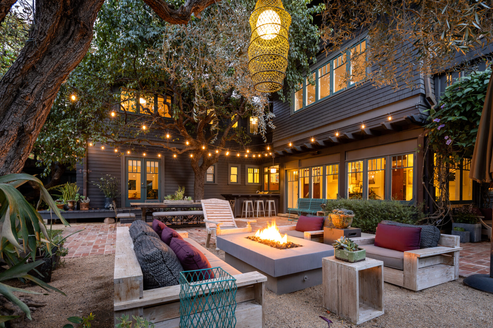 streaming lights cross over a fire pit in the backyard of a Santa Monica Craftsman-style home at 405 Palisades Ave