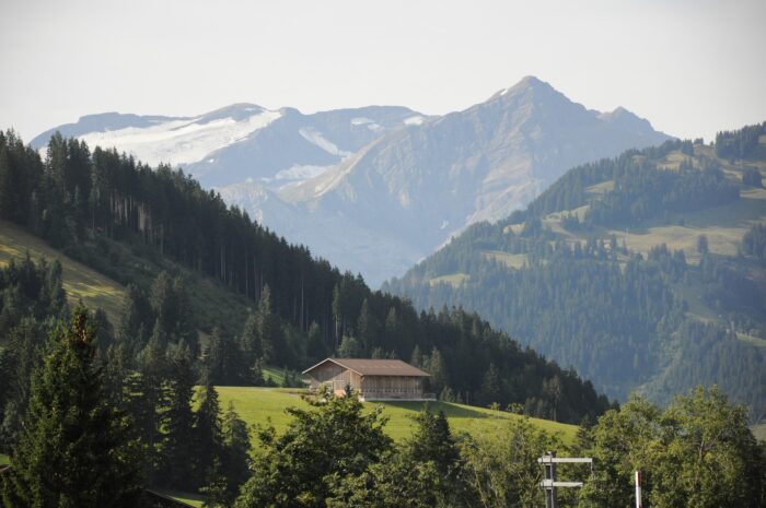 mountains sit in the backdrop of a chalet in gstaad, switzerland