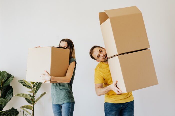man and wife juggle moving boxes while selling their home