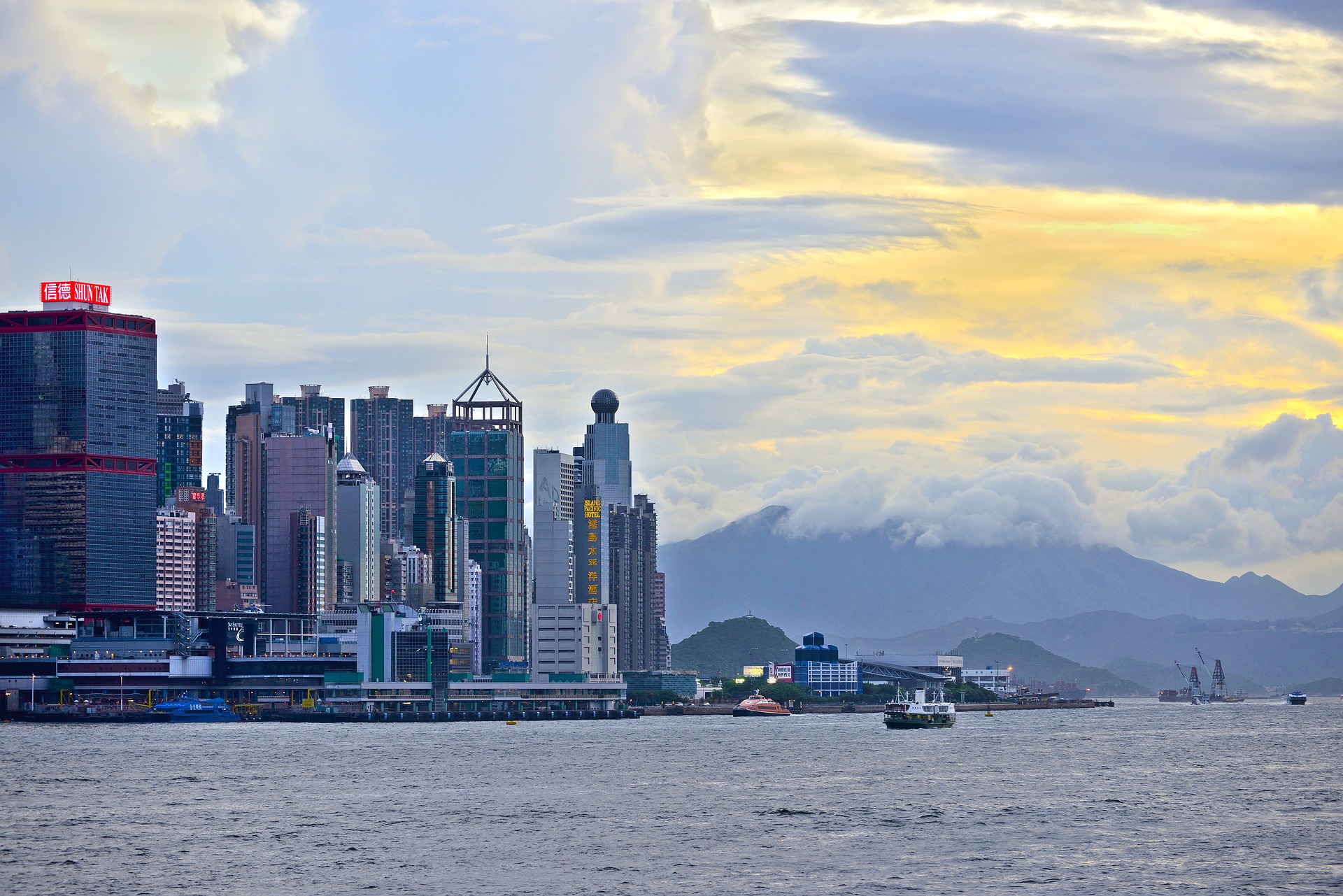 hong kong skyline overlooking the waterway with boats and clouds in background