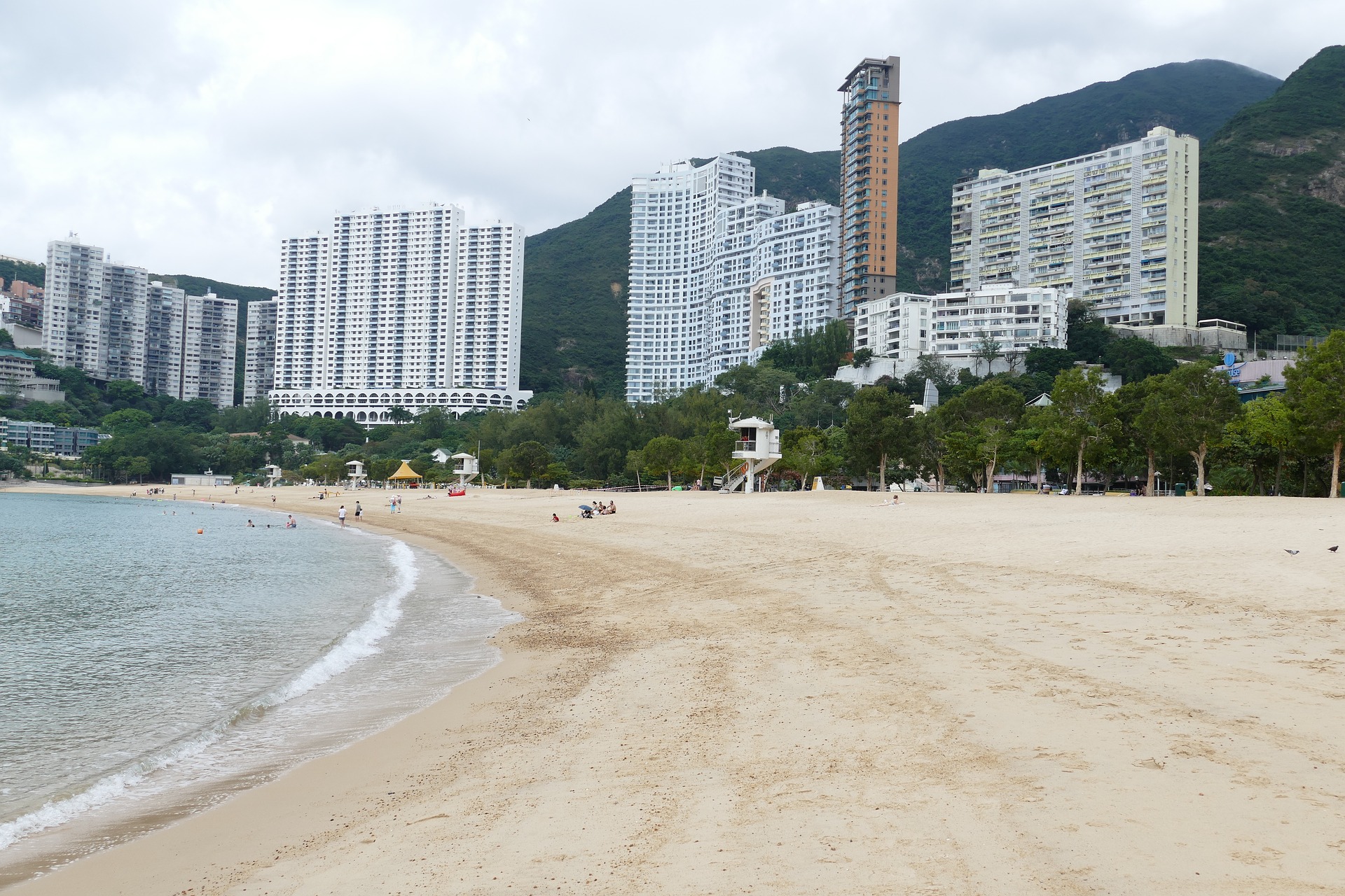 beachfront cove in hong kong with skyscrapers and jungle in the background