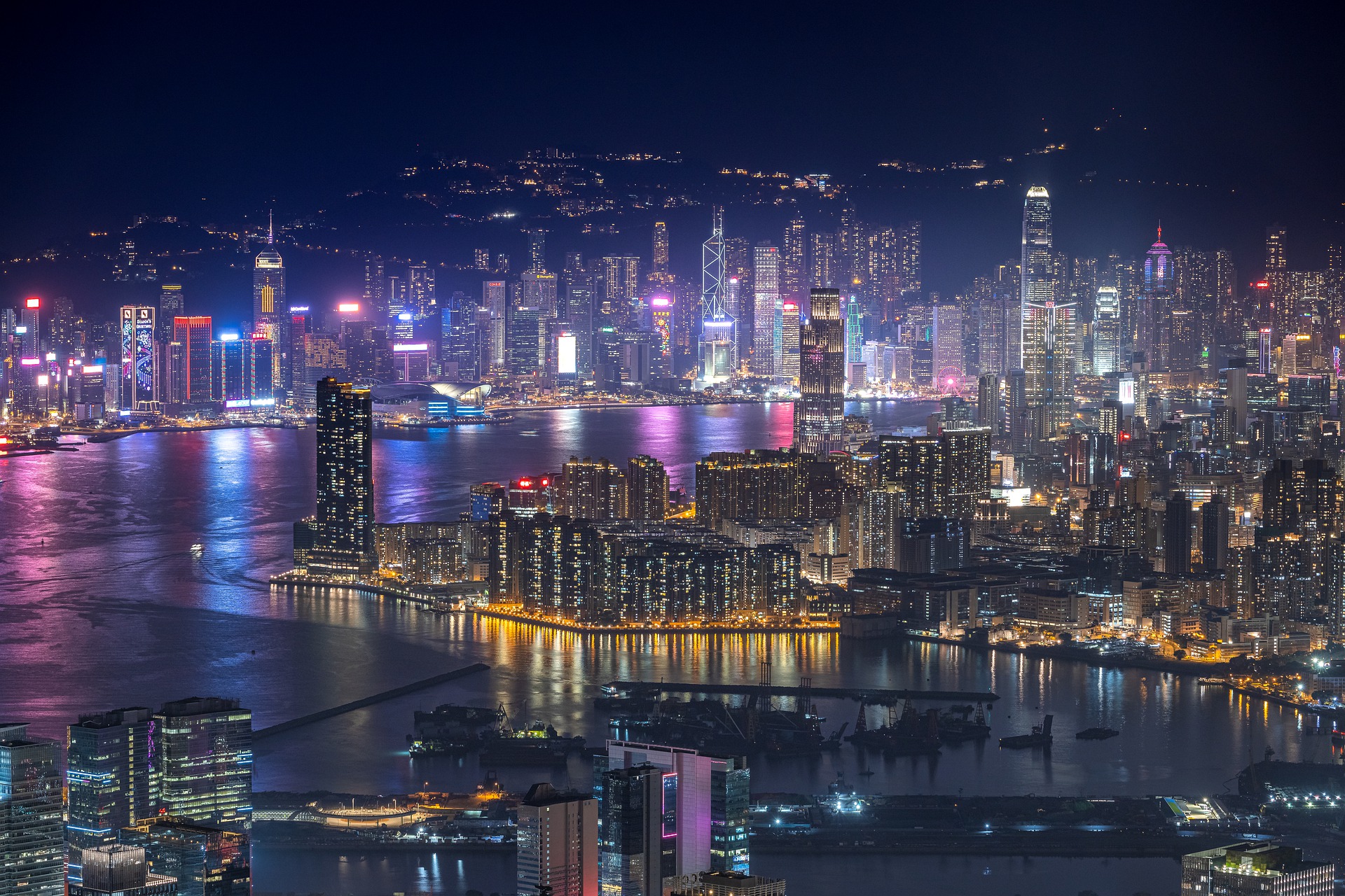 the hong kong skyline and waterway at night with glowing neon lights and skyscrapers