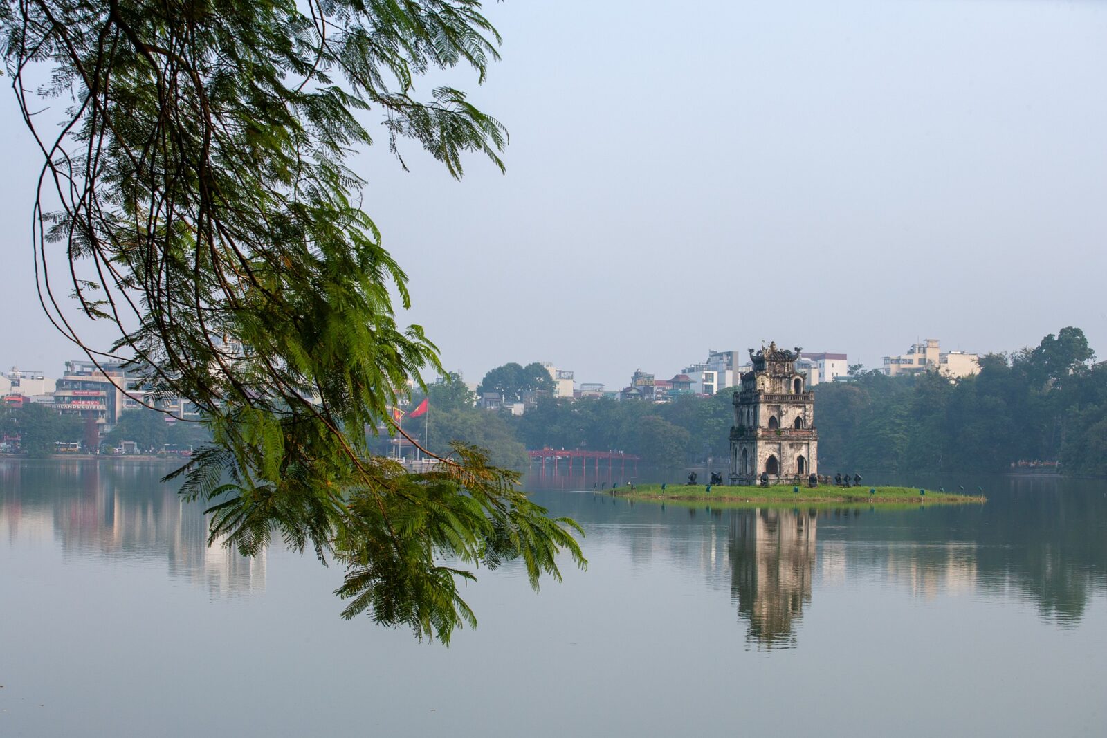 turtle tower in vietnam from afar across the lake with cityscape in background