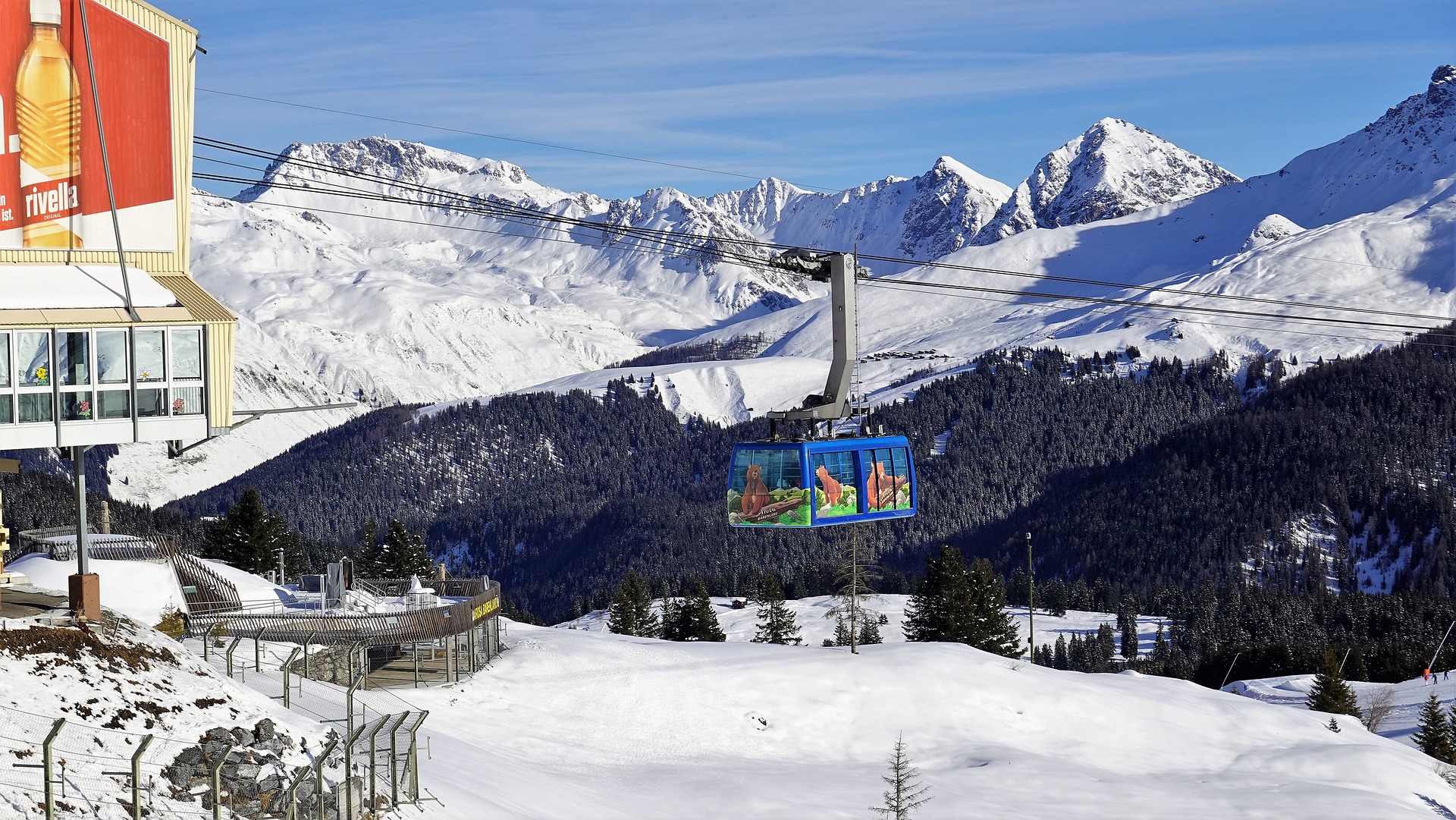 cable car moving in the swiss alps with snow-covered mountains in background