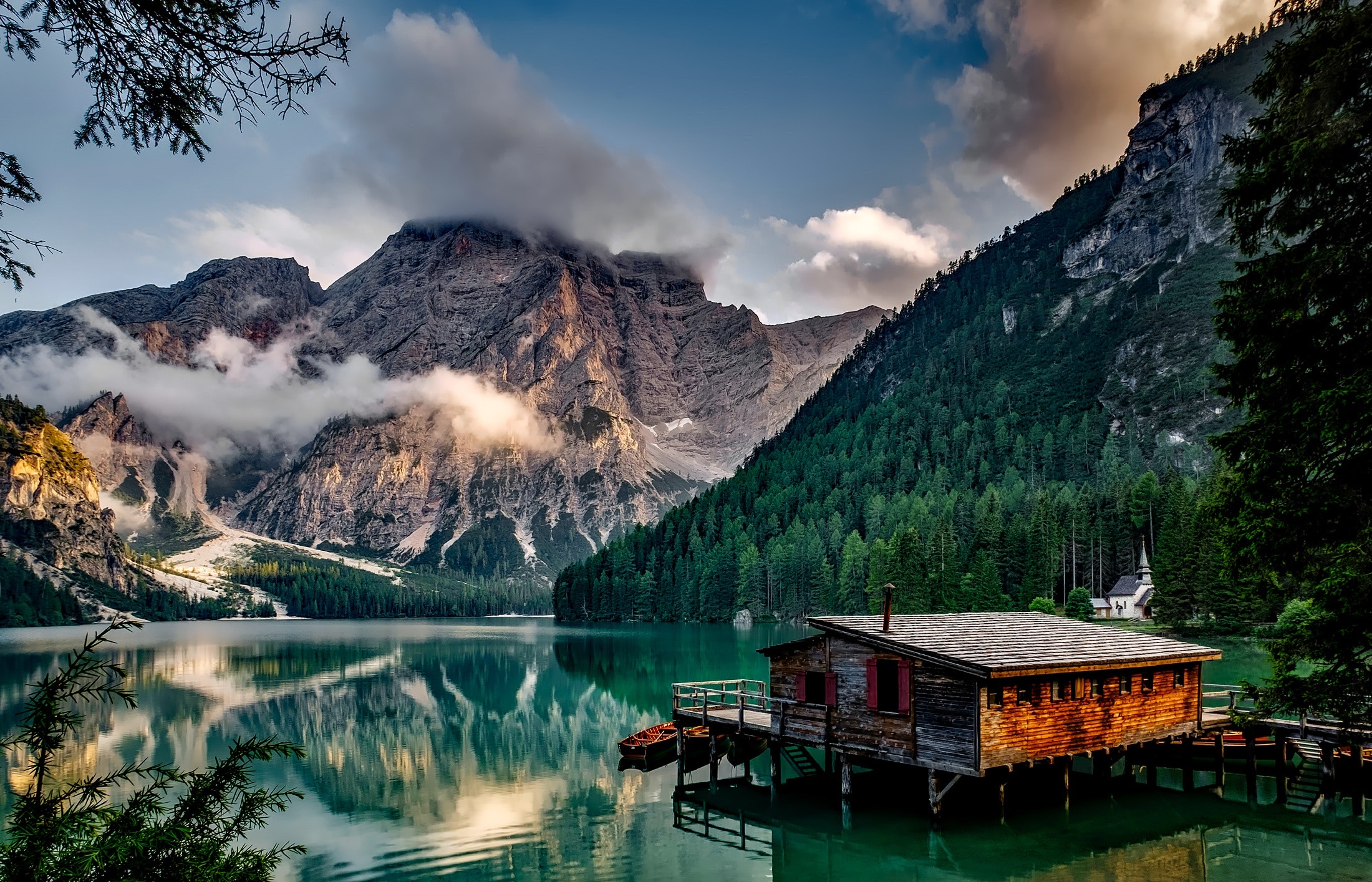 a cabin sitting on a emerald green lake with mountains in the background