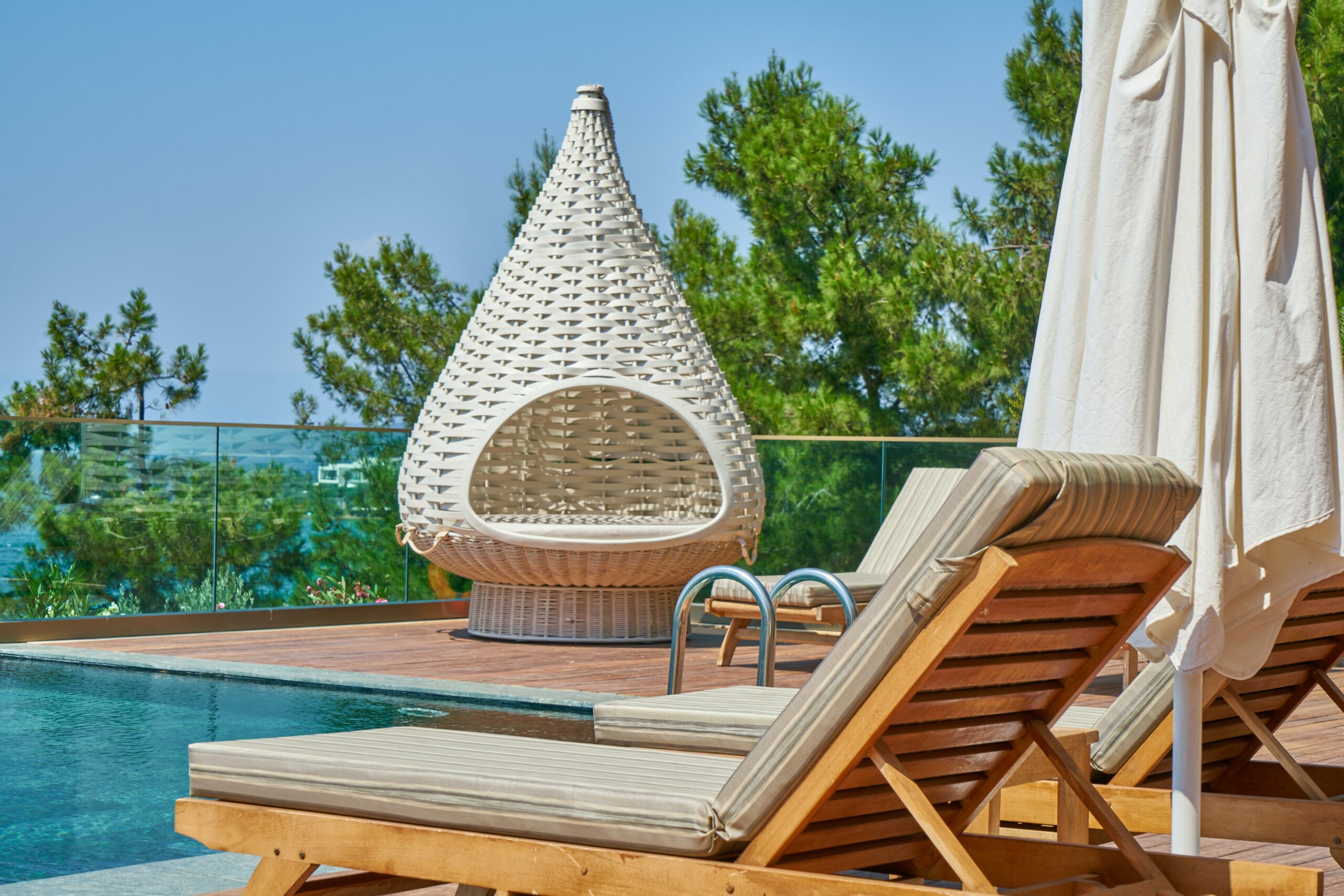 lounge chairs sit in the foreground of a swimming pool