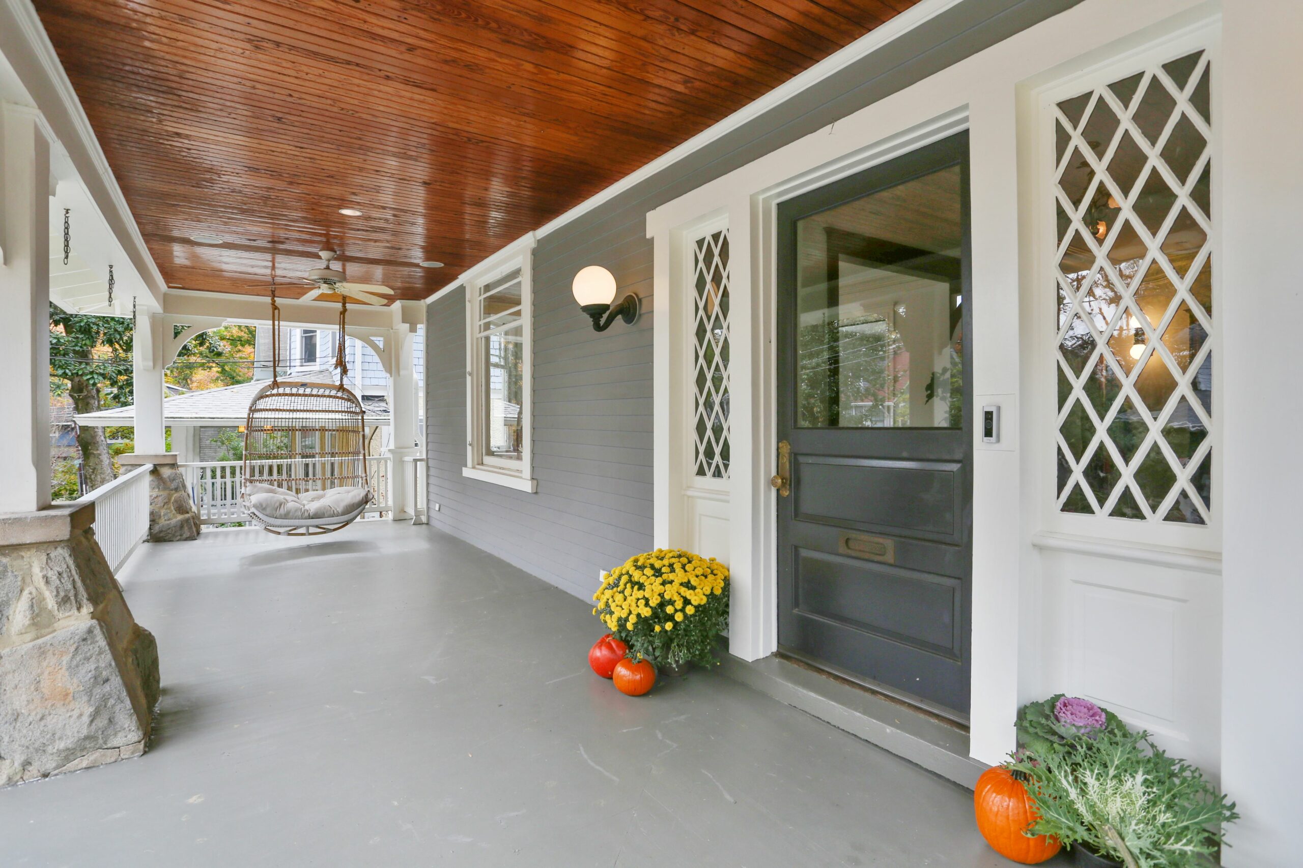 Exterior view of a home's porch with a rattan hanging chair.
