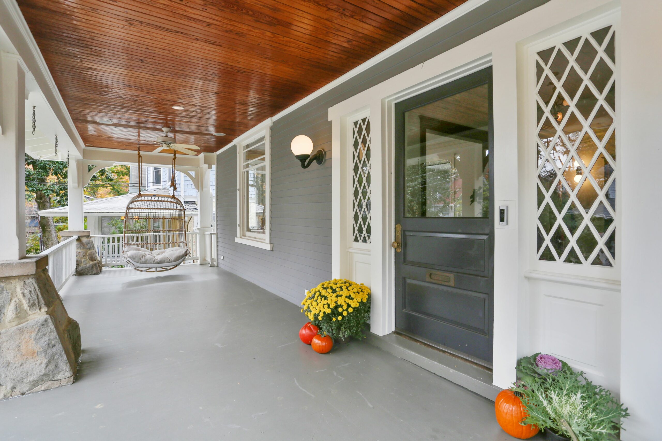 Exterior view of a home's porch with a rattan hanging chair.