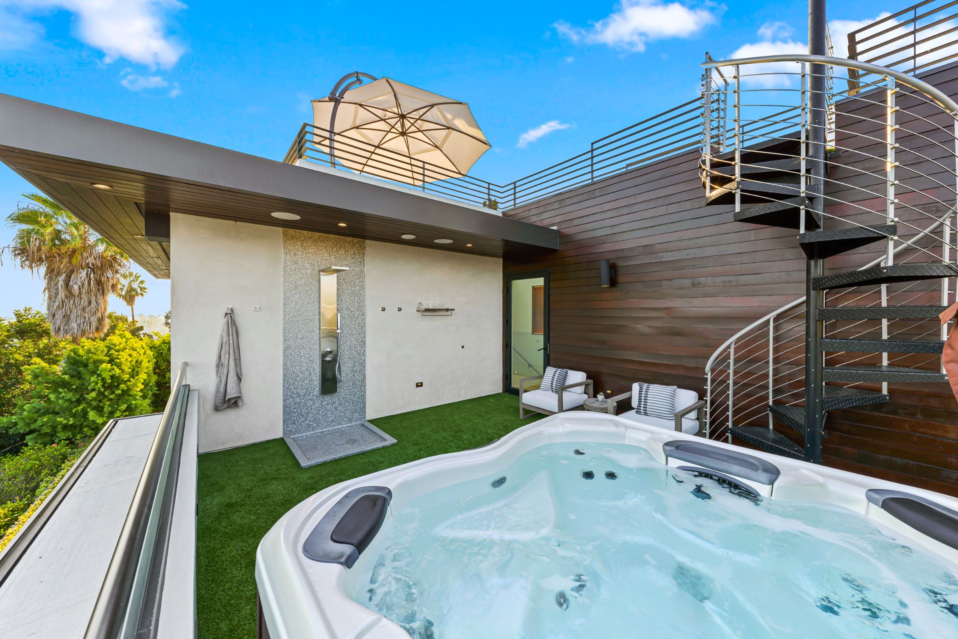 Exterior view of a home with a hot tub and spiral staircase. 