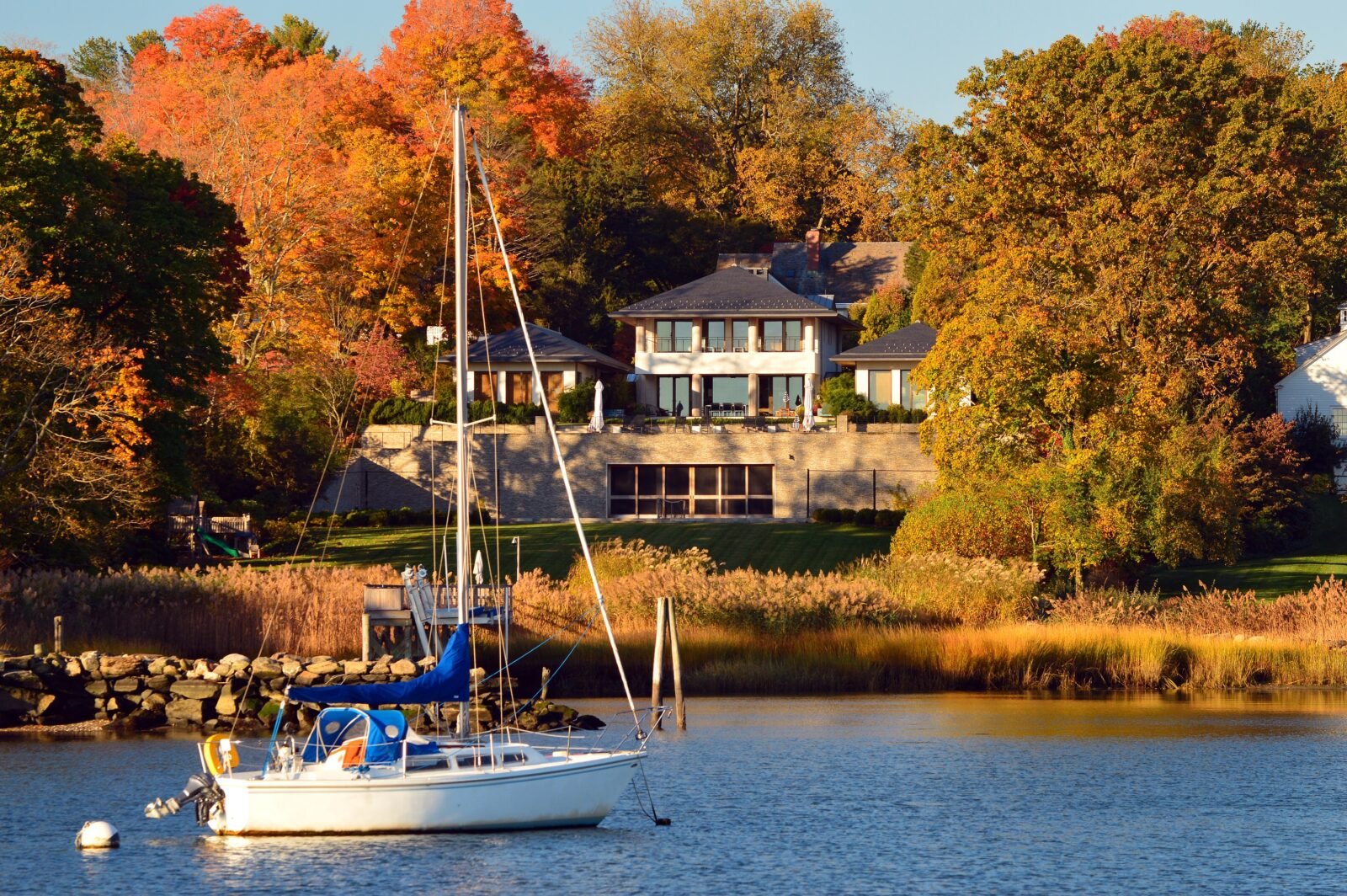 Sailboat Sits In Front Of Waterfront Mansion And Trees