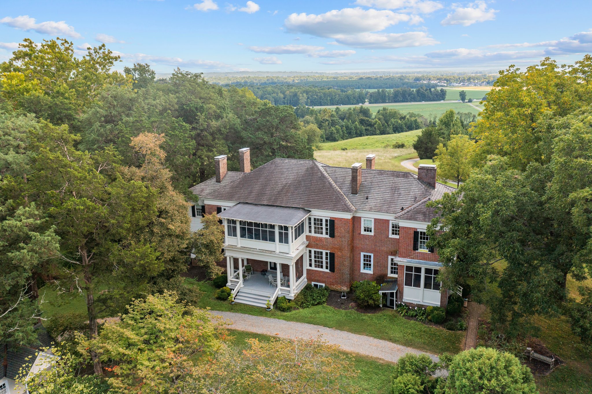 A two story, red-brick estate surrounded by trees.