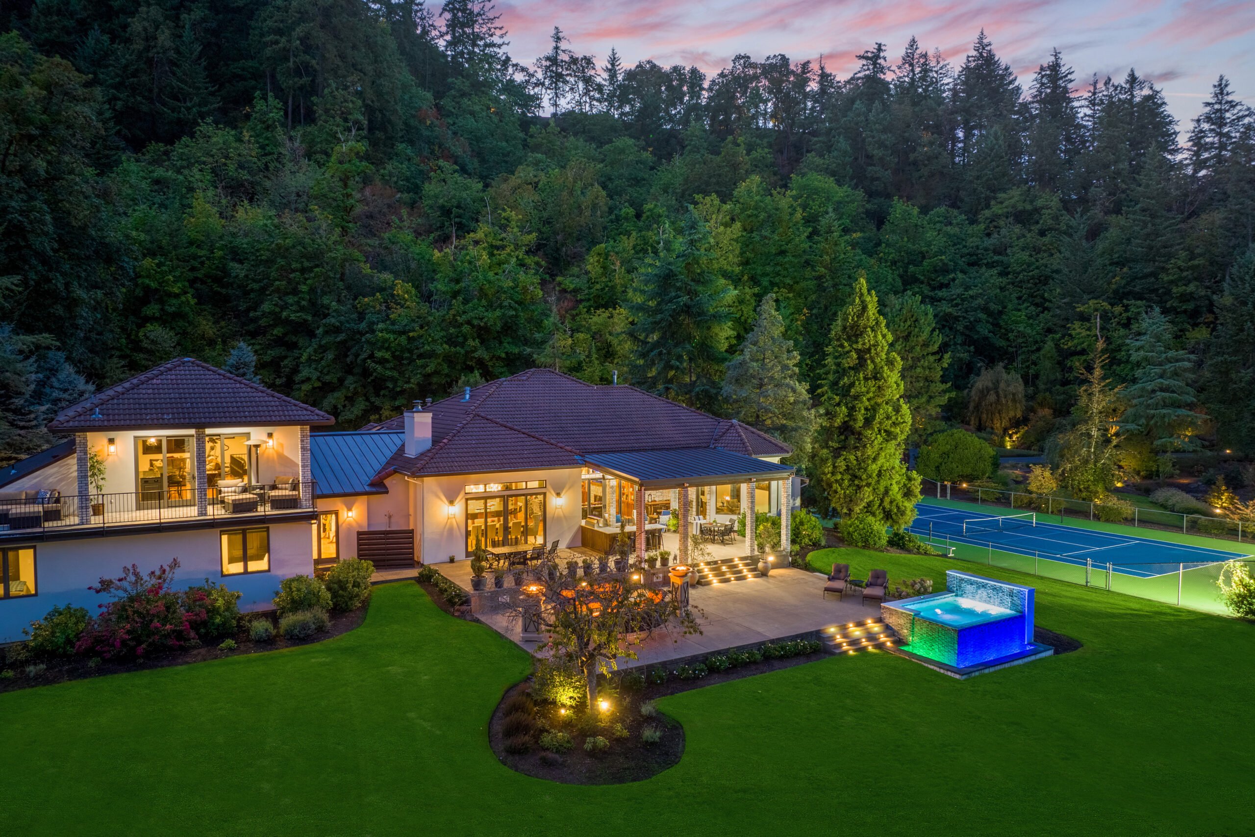 A big house with a green lawn in front of many trees. 