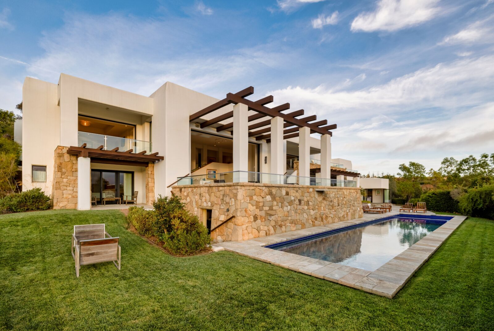 A sideways view of a concrete house with brick siding and a pool.