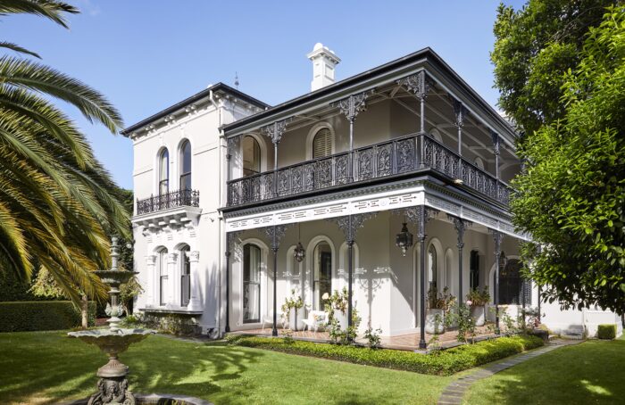 A fancy white house with Victorian architecture and a fancy fountain.