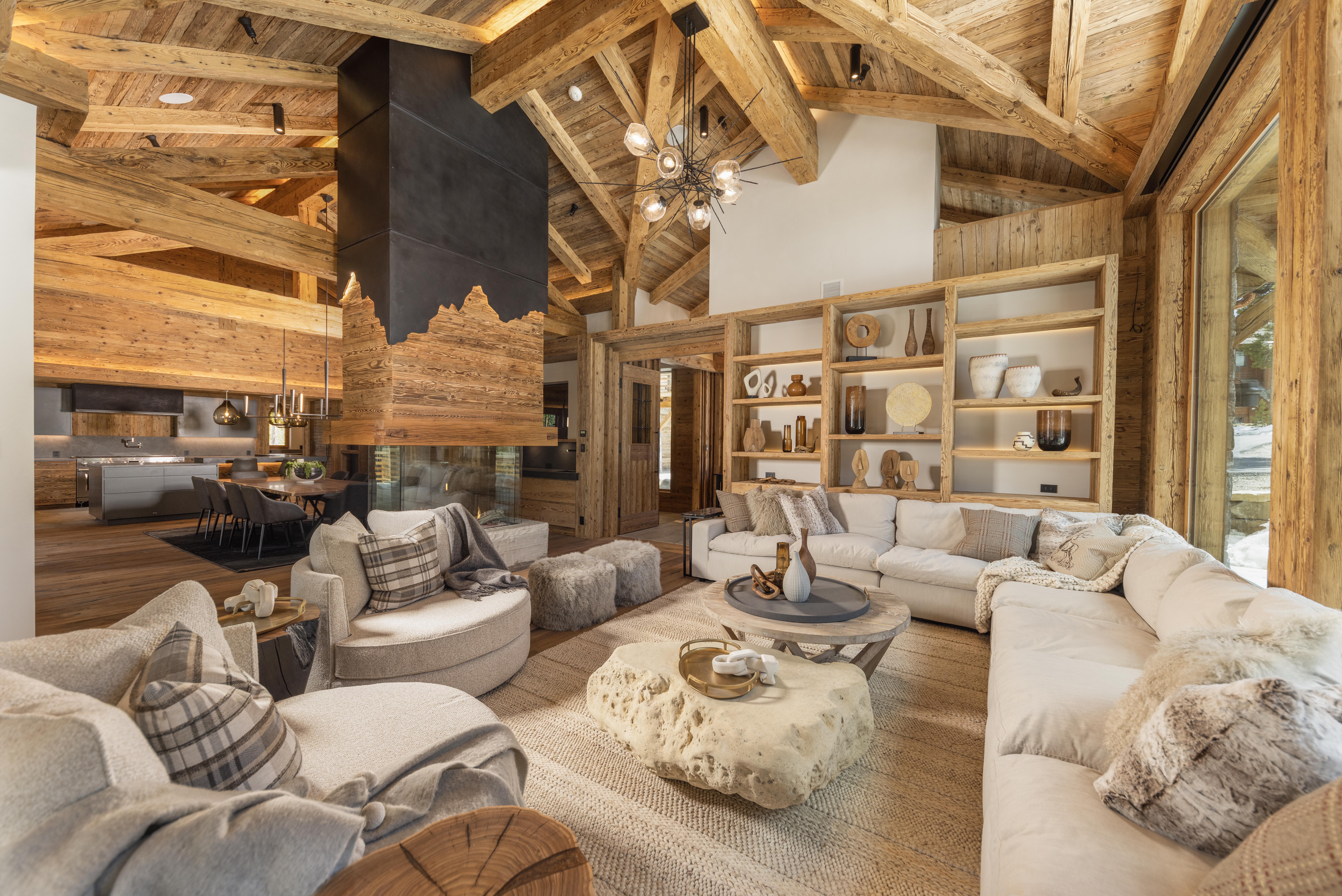 A rustic wood living room and kitchen centered around a fireplace.