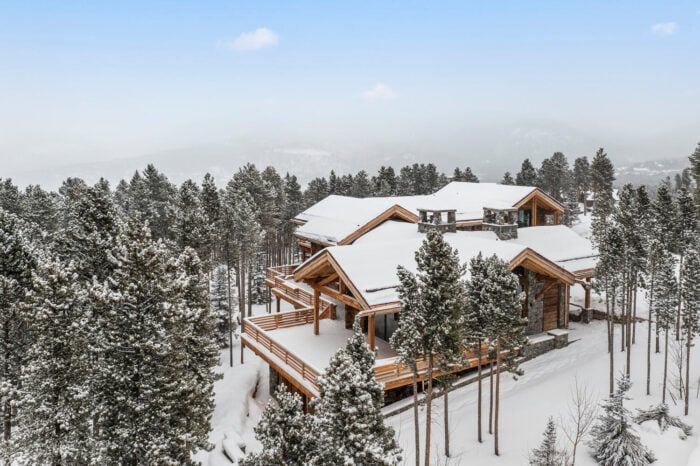 A chalet in a snowy clearing surrounded by trees.