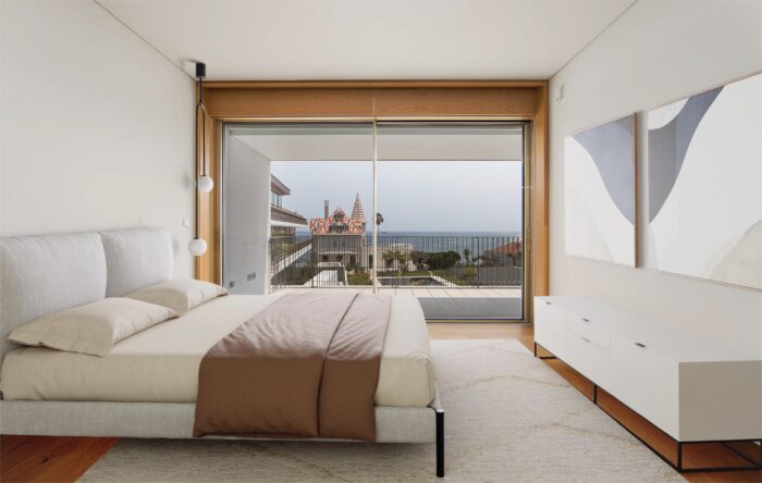 Bedroom with oak floors and floor-to-ceiling windows featuring ocean views. 