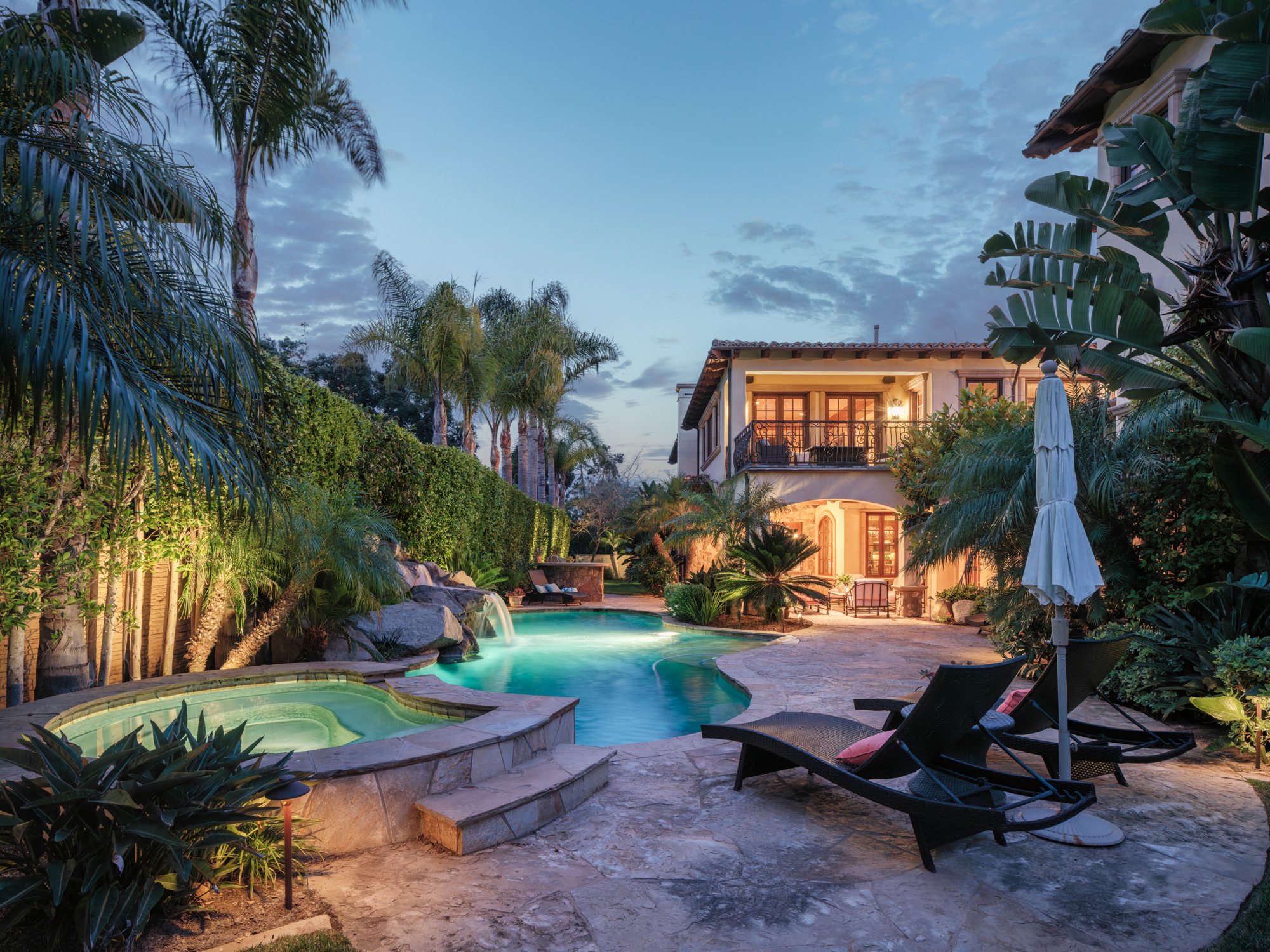 An outdoor area with a pool, reclining chairs, and a canopy of trees.