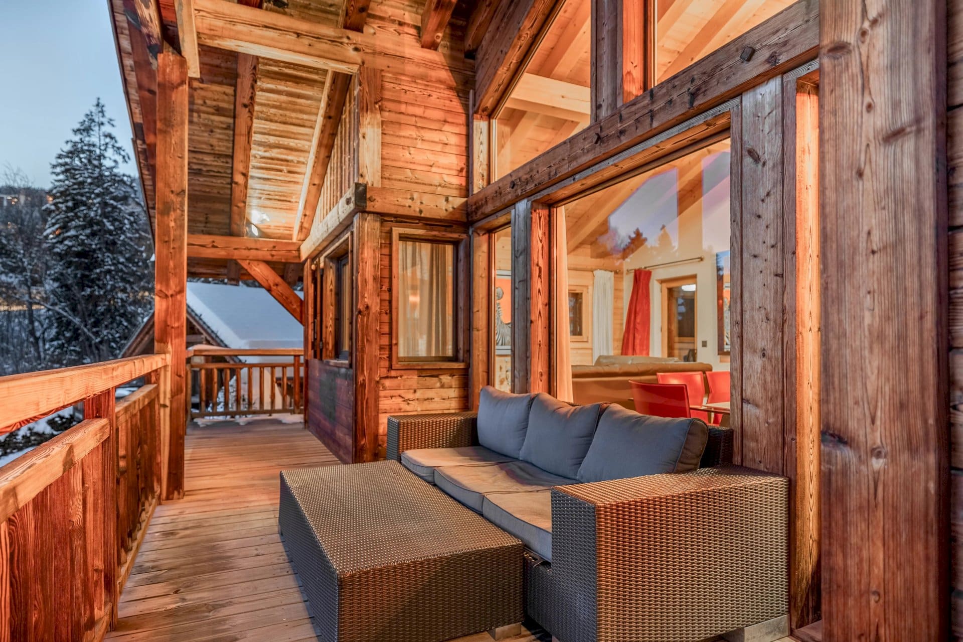 A sideways view of the bright wooden porch of a chalet, with a futon.