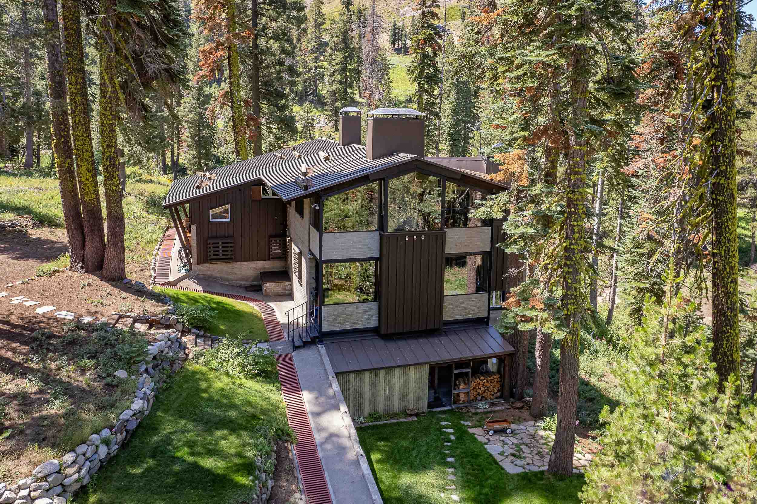 A two-story lodge on a hill surrounded by pine trees.