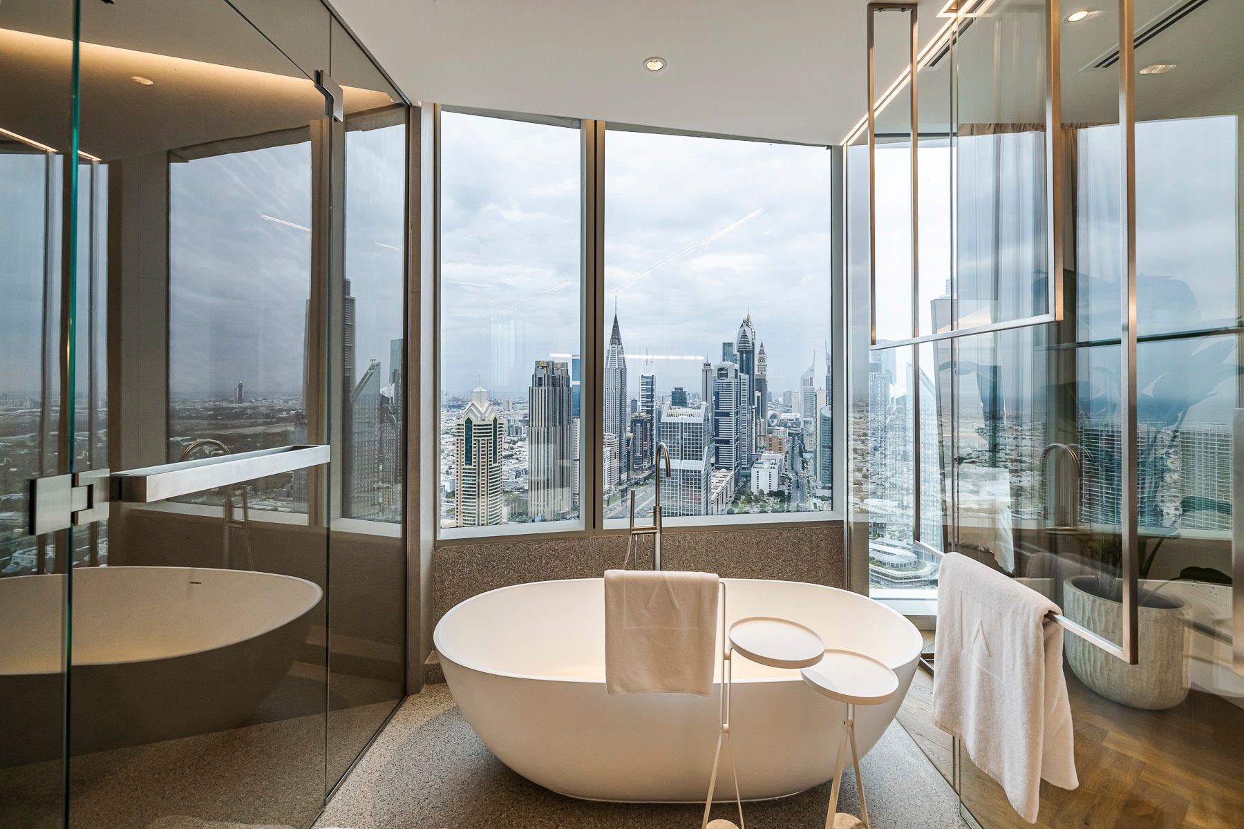 A bathtub in front of a window showing a vast city skyline