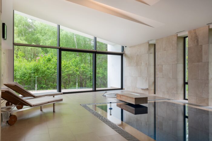 A pool positioned in front floor-to-ceiling windows