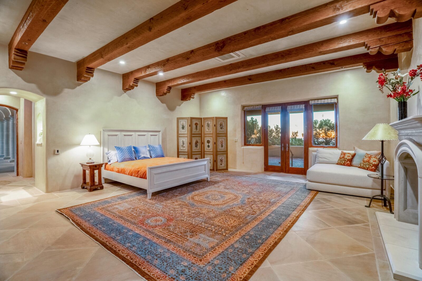 A spacious primary living suite with fireplace, ceiling beams and outdoor access. 