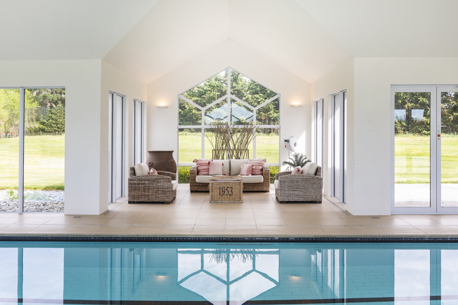 A sitting area with couches perched in front of a pool between big windows.