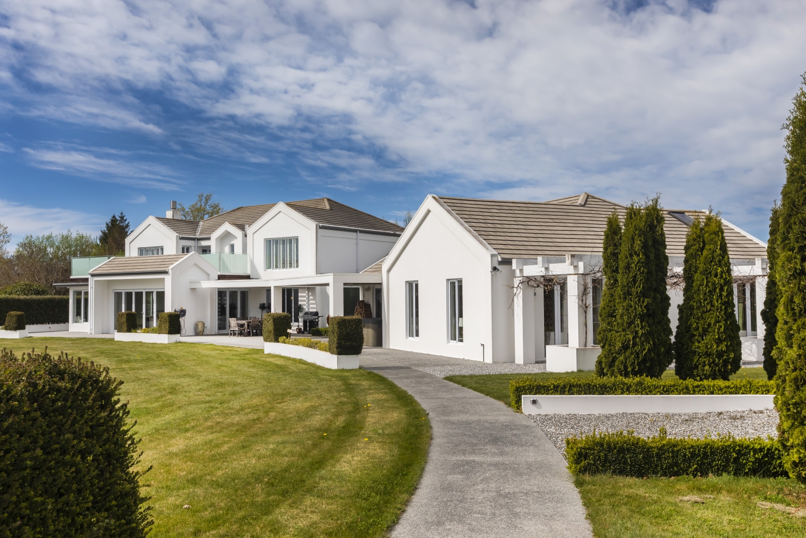 A pathway leading to a big white house with a big yard