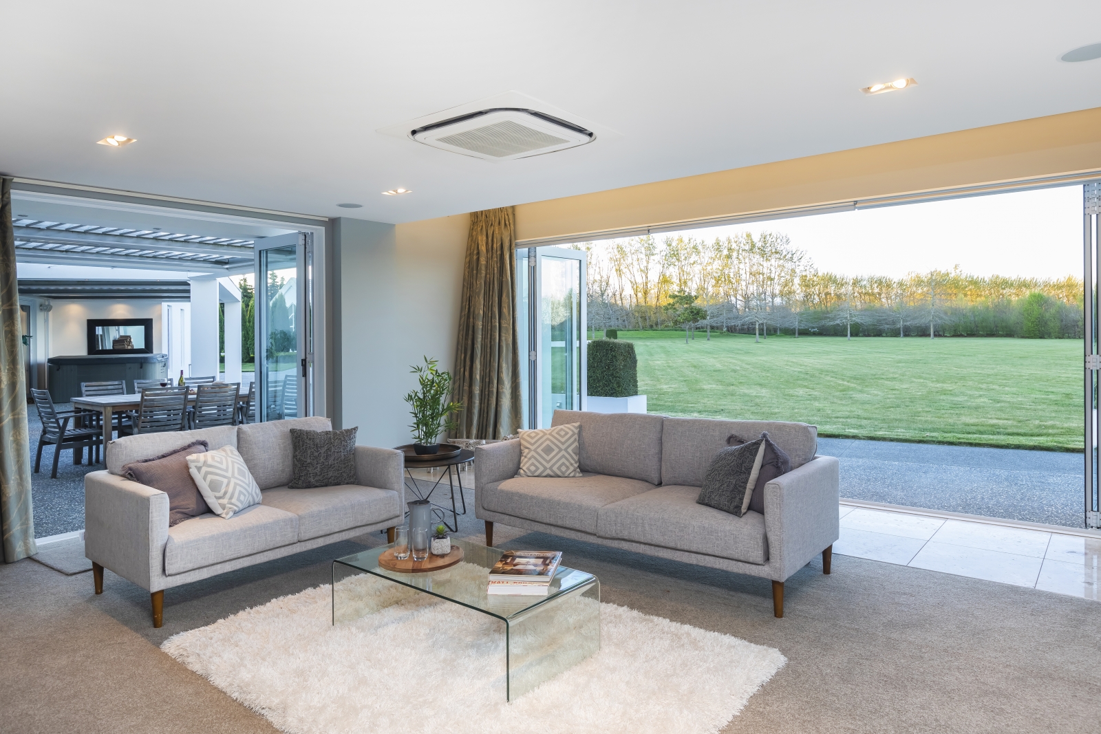 A living room with a dining area behind it that opens up to a vast backyard.