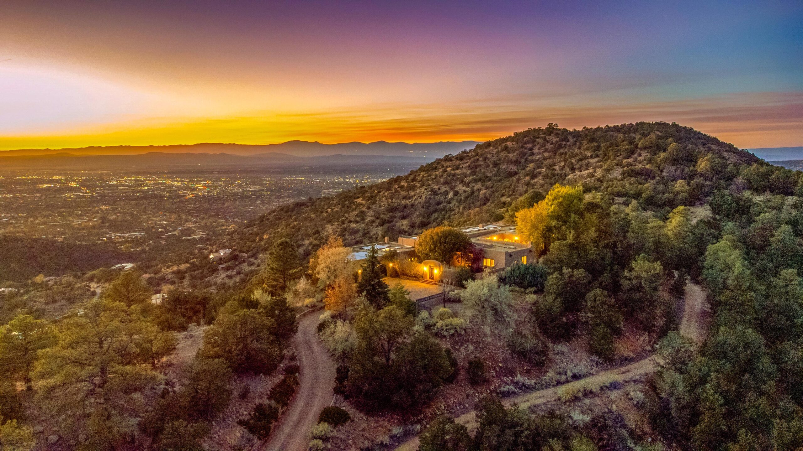 A sprawling view of a big hill during the sunset with a stone house resting there.