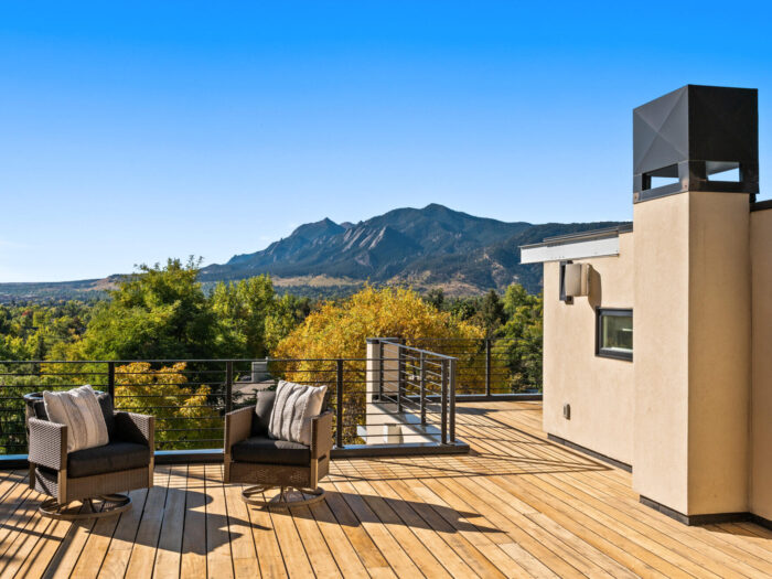 The outside deck of a property that oversees the top of some trees and a distant mountain.