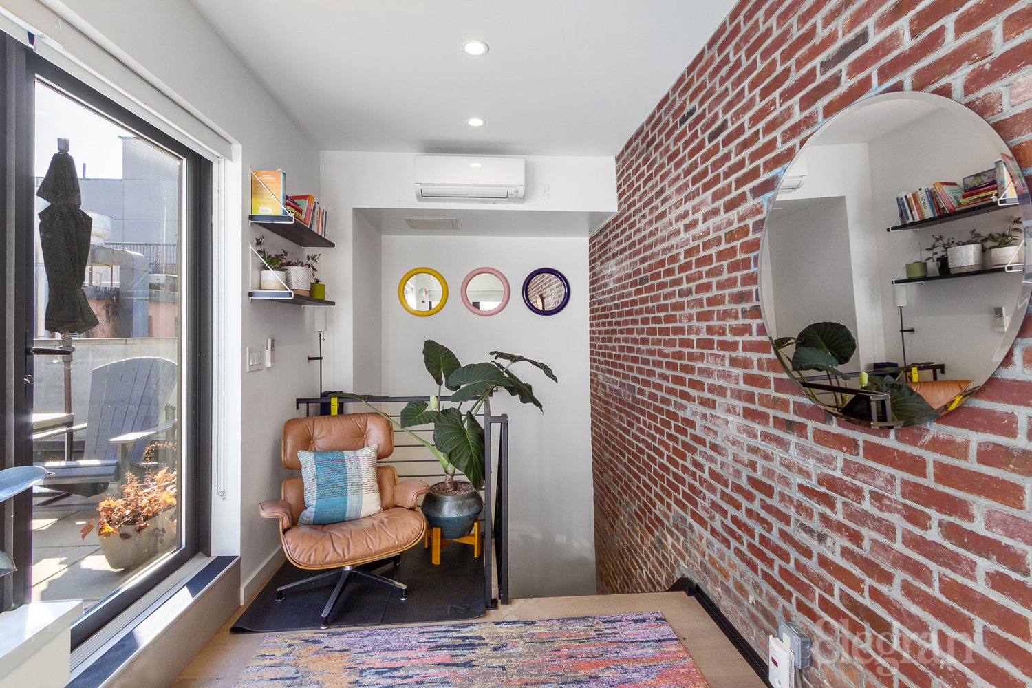 A sitting area with mirrors, a window, and a brick wall.