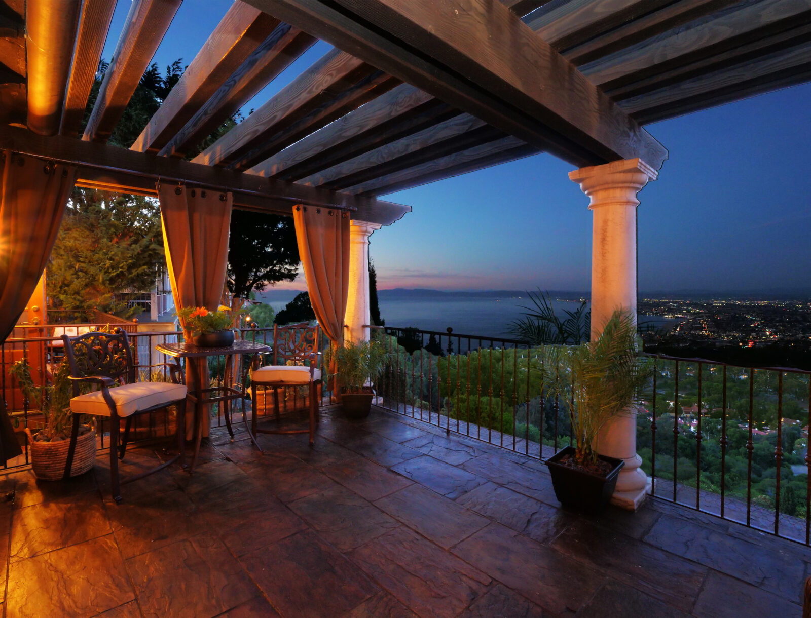 A patio deck with a view of the setting sun and darkening skies over the ocean.