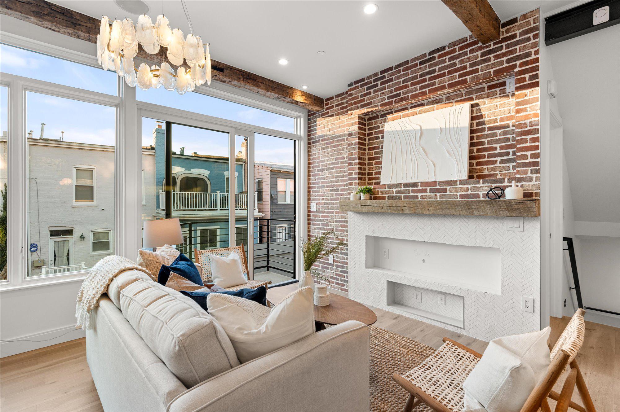 A cozy living room with a big window wall on one side and a brick wall on the other.