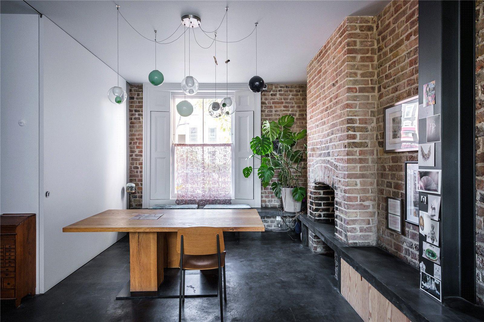 A studying room with a desk, a brick fireplace, and several hanging glass decorations.