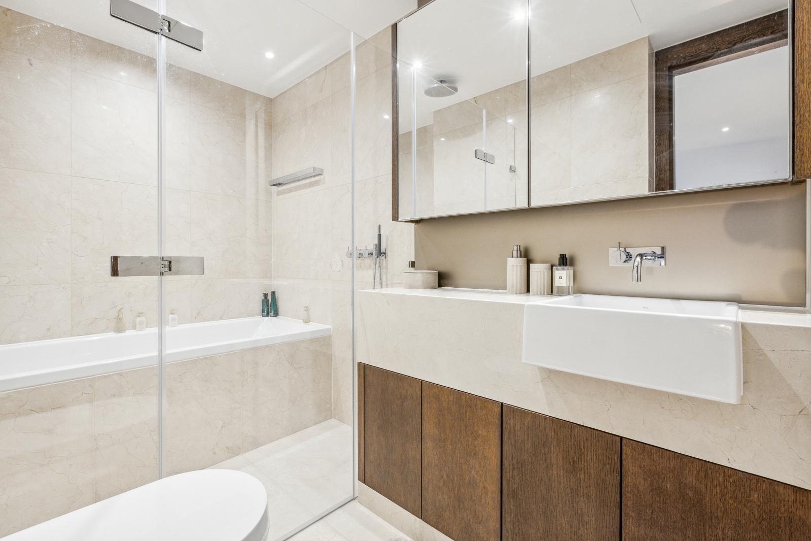 Sleek bathroom with marble and wood cabinetry. 