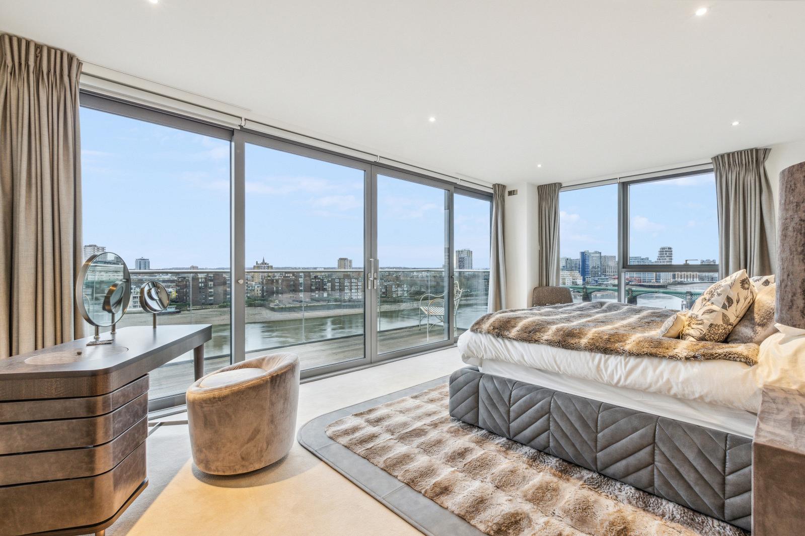 Bedroom with floor to ceiling windows and private balcony. 