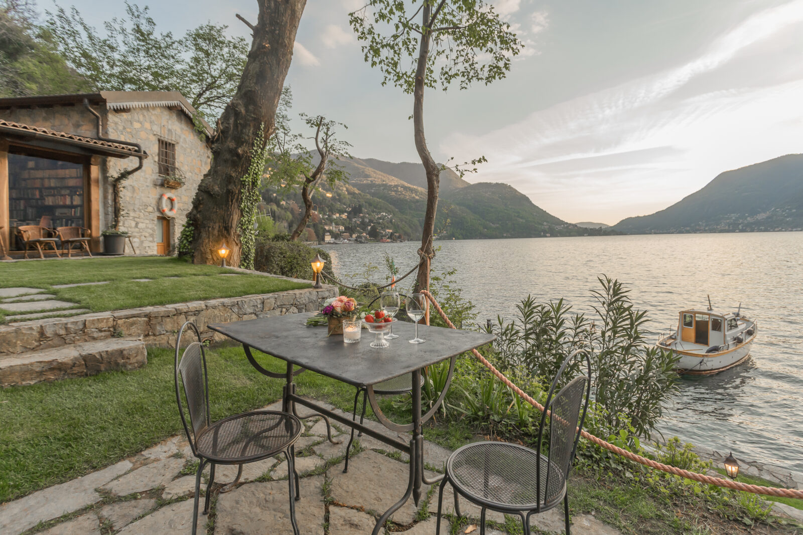 An outdoor table set up in front of a lake with a house in the background as well