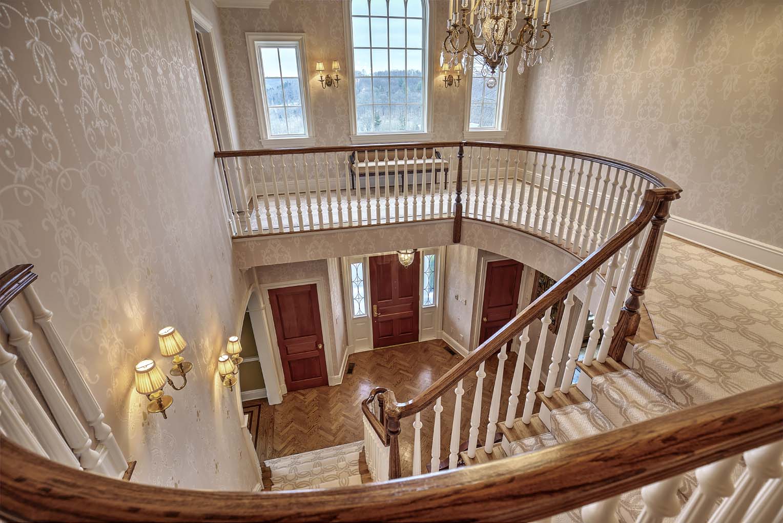 A walkway and a staircase above an entrance on herringbone floor.