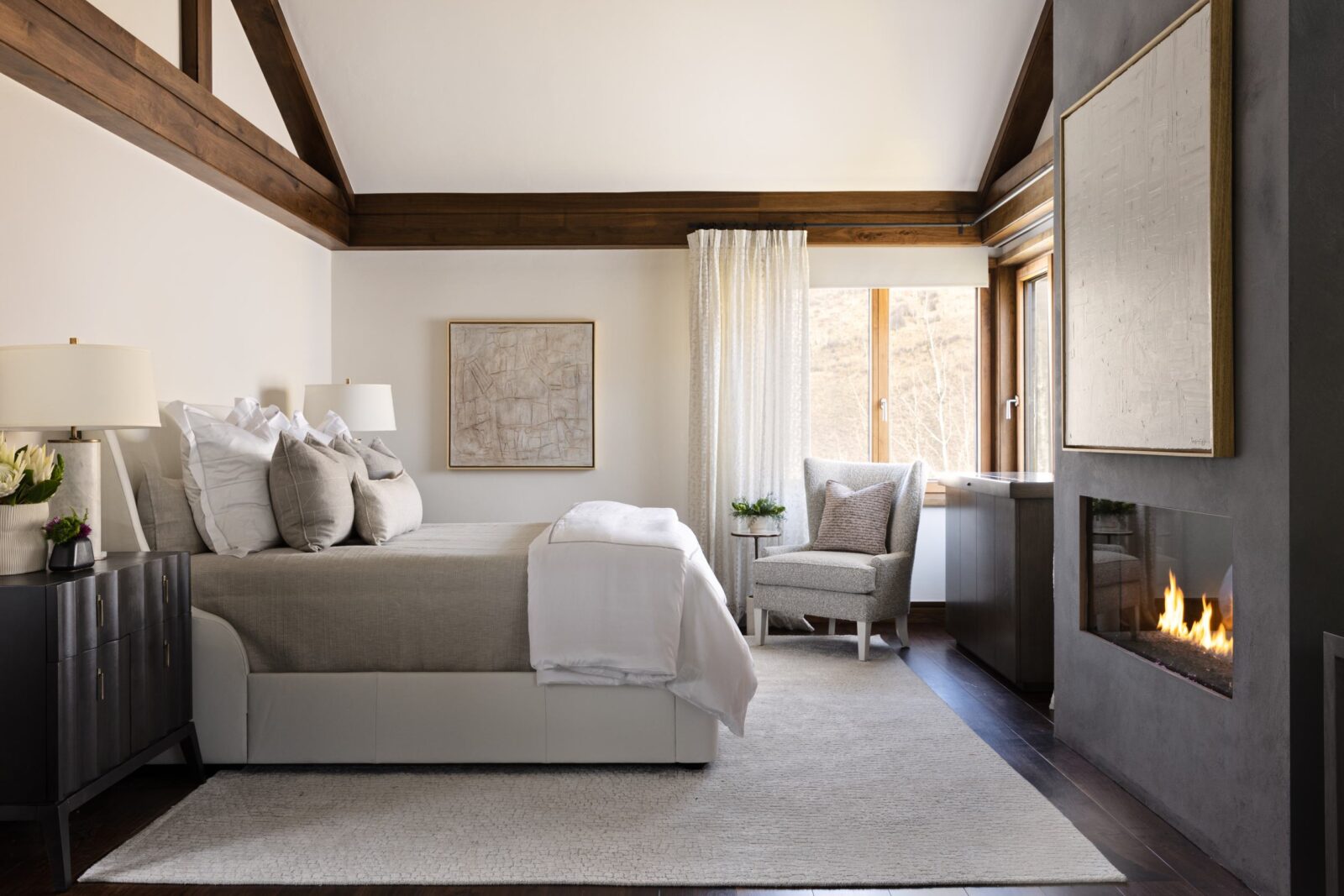 A bedroom with vaulted ceilings and a sleek fireplace. 