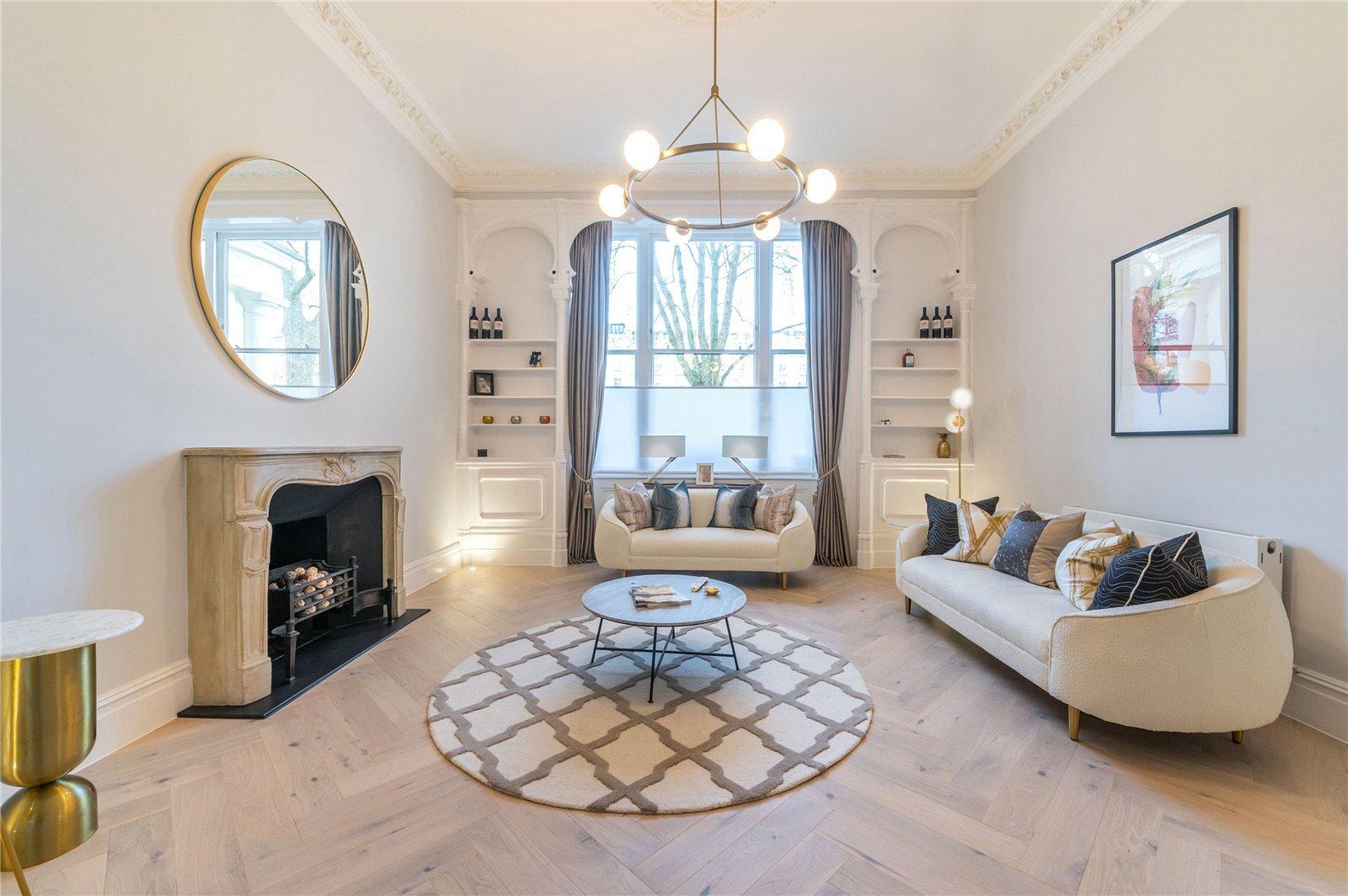 A white living room with a fireplace and a herring bone styled floor.