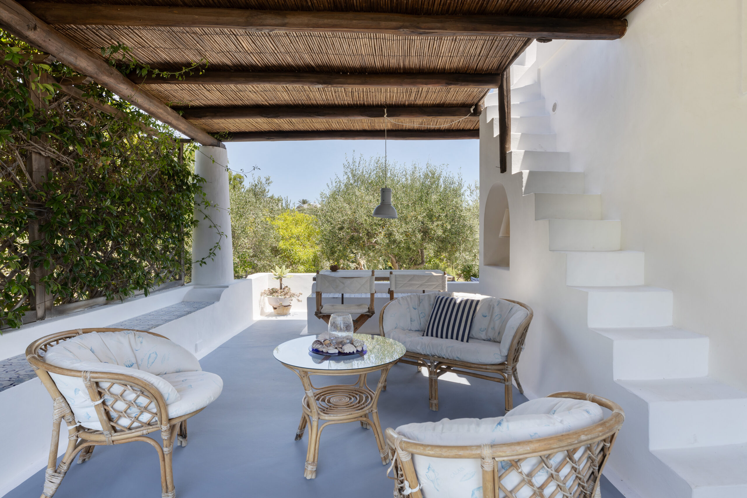 A shaded outdoor sitting area next to a white marble staircase and house