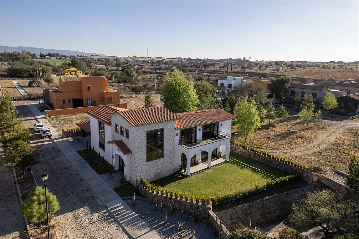 A house with a green yard with more houses on different sides of it.