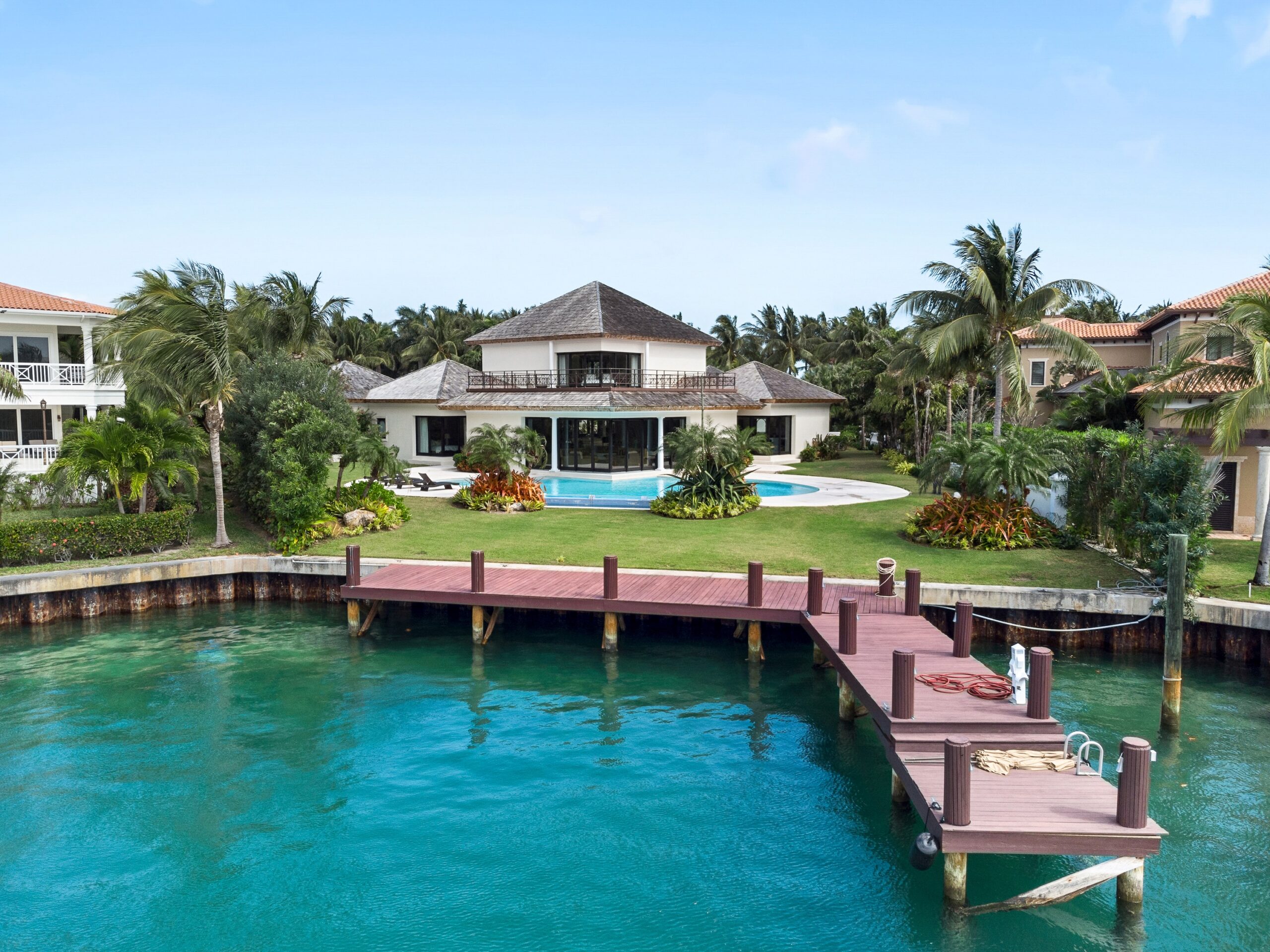 A house with a green yard, a pool, and a dock on the water.