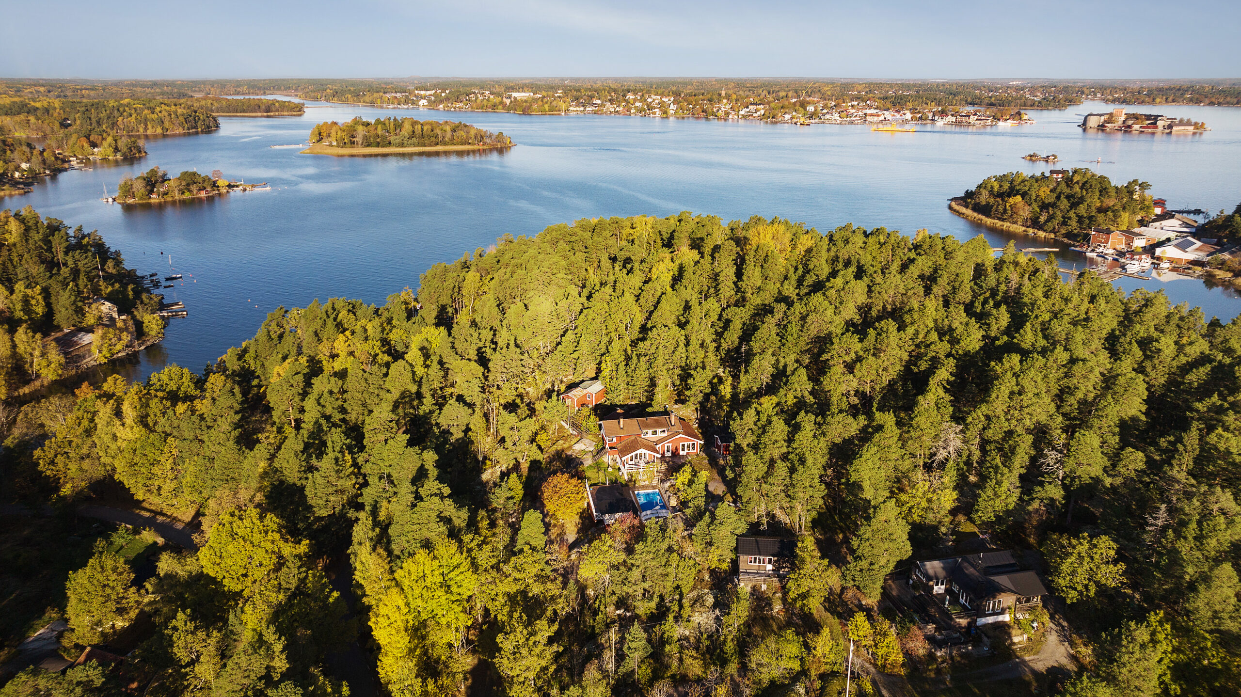 An aerial view of A big home surrounded by trees with a big river in the background.
