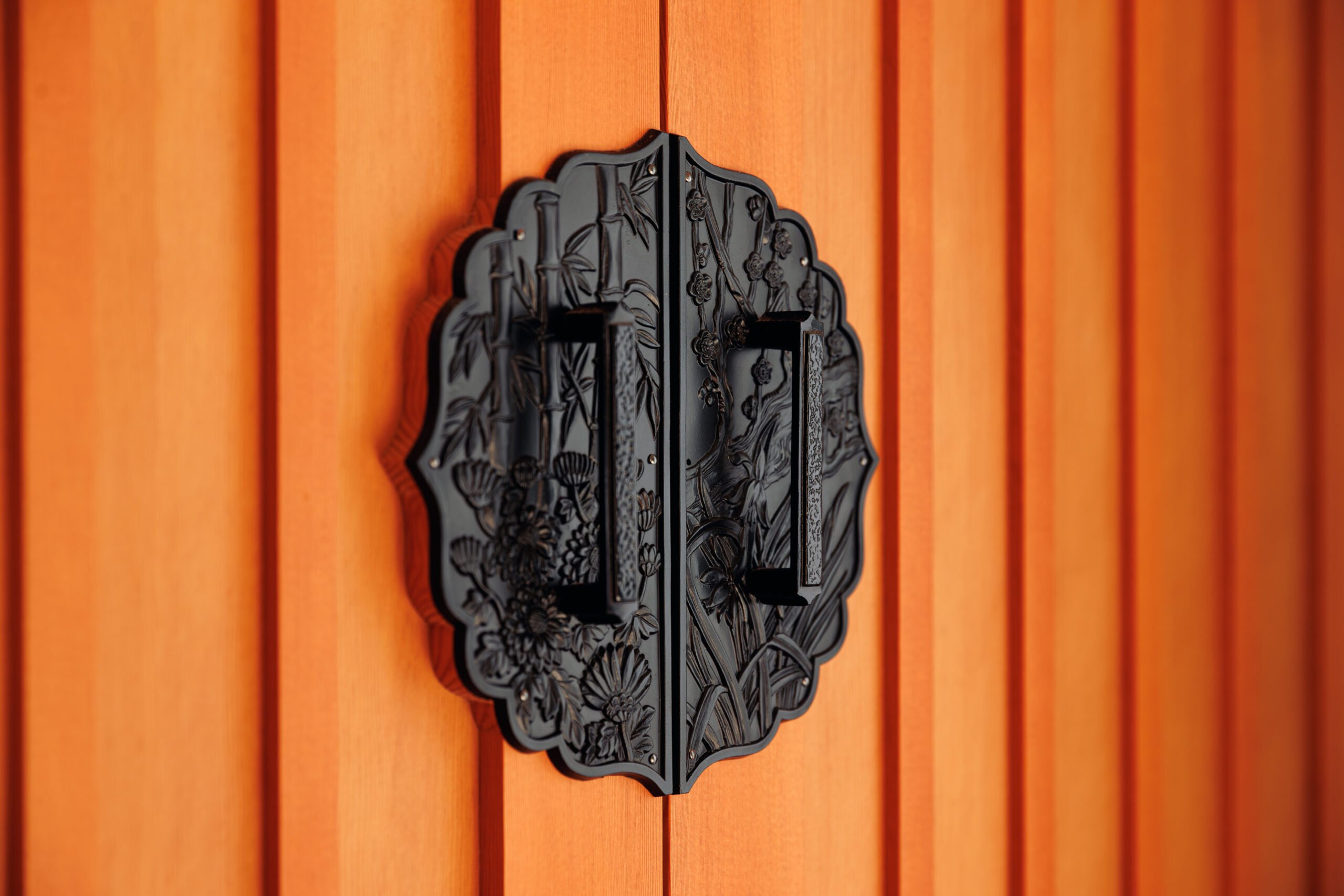 Orange door with elaborate etching metal handles. 